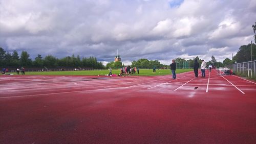 People running on field against cloudy sky