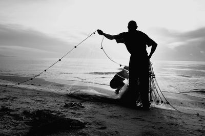 Silhouette man and woman fishing at beach