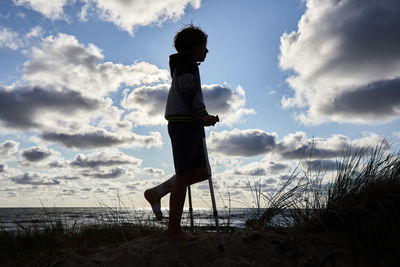 Side view of woman standing on beach against sky