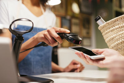 Close-up of customer paying cashless with smartphone at counter of a store