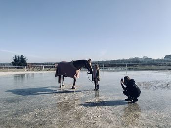 Friends standing in the sea against clear sky