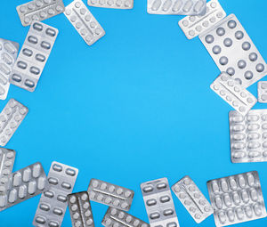 High angle view of medicines in blister pack against blue background