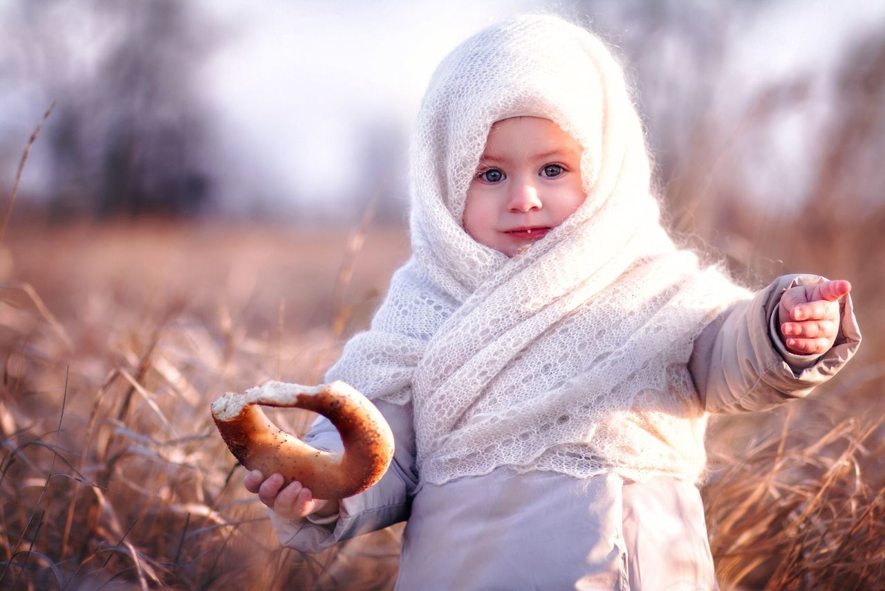 one person, winter, portrait, looking at camera, child, clothing, childhood, warm clothing, land, real people, holding, focus on foreground, nature, field, innocence, day, cute, cold temperature, outdoors, scarf