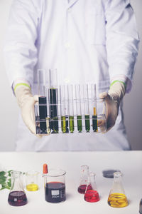 Midsection of scientist holding test tubes in laboratory