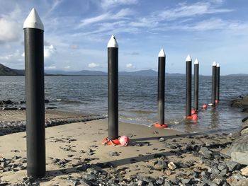 Wooden posts on beach against sky