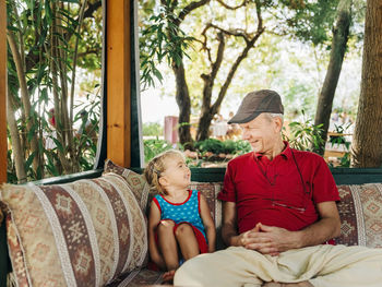 Grandfather and daughter sitting on sofa at home