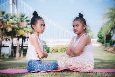 Angry sisters sitting on yoga mat at park