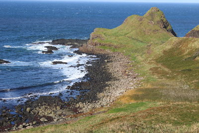 Scenic view of sea by cliff against sky