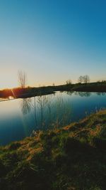 Scenic view of lake against clear sky during sunset