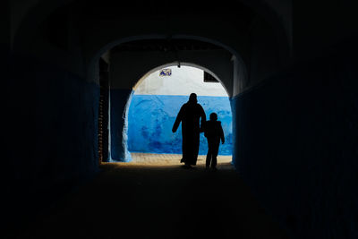 Rear view of silhouette people walking in tunnel