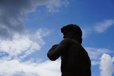 Low angle view of male sculpture against sky