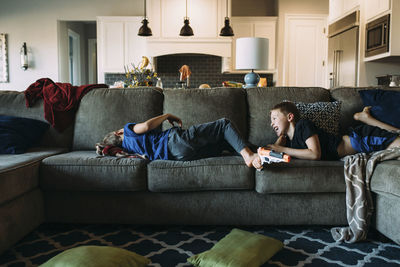 Happy brothers lying on sofa at home