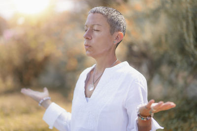 Woman with eyes closed meditating outdoors