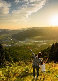 Rear view of people standing on mountain against sky