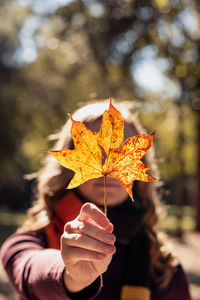 Close-up of girl covering face with leaf