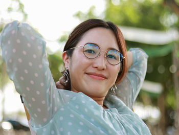 Red-haired woman in green shirt and eye care glasses sitting happy smiling looking outdoor 