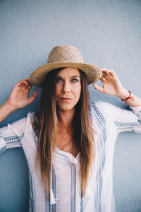 Woman wearing hat against wall