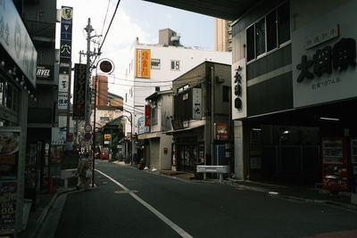 Road by buildings in city against sky