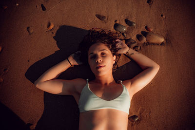 High angle portrait of woman lying on shore at beach