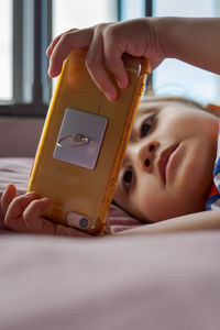 Cute little girl is watching videos on smartphone on the bed.