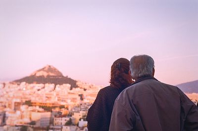 Rear view of man and woman standing on mountain against clear sky