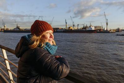 Senior woman looking away by elbe river at harbor