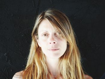 Portrait of young woman against black background