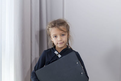 Portrait of smiling girl standing against wall