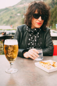 Portrait of mid adult woman sitting by beer glass on table