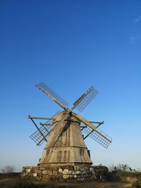 Low angle view of traditional windmill against clear blue sky
