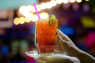 Cropped hands holding red drink in glass