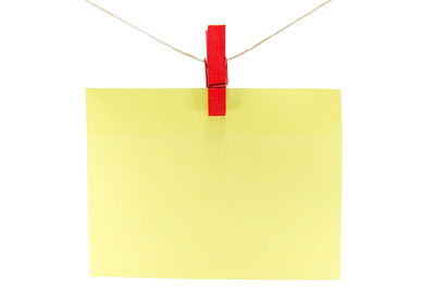 Close-up of clothespins hanging on paper against white background