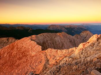 Morning view over apine cliff and sun at horizon. mountains increased from foggy background