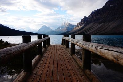 Wooden pier over lake against mountains