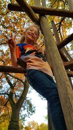 Low angle view of smiling girl against tree