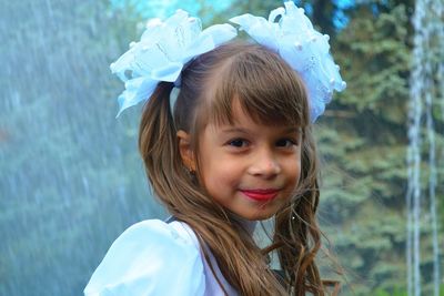 Portrait of cute smiling girl standing against waterfall