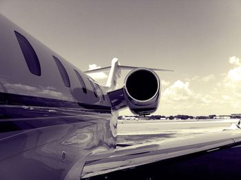 Close-up of airplane flying over runway against sky