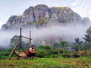 People sitting on land by trees against mountains