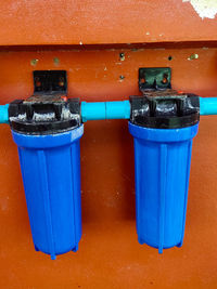 Close-up of blue garbage bin against wall