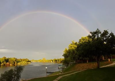 Scenic view of rainbow over river against sky
