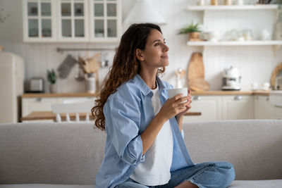 Young woman using mobile phone while sitting at home