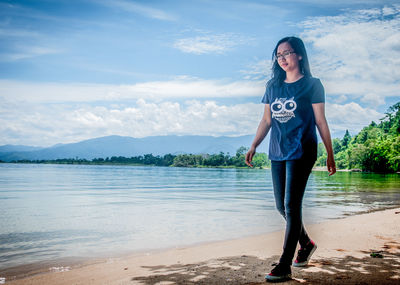 Portrait of young woman standing against sky