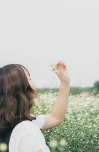 Midsection of woman holding flower on field