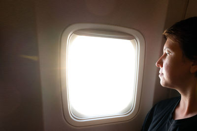 Side view of woman looking through window