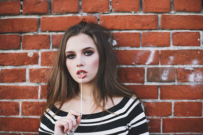 Portrait of young woman against brick wall