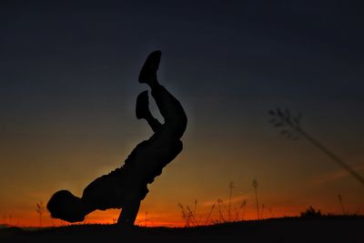 Silhouette man exercising on field against sky during sunset