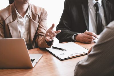 Midsection of man using mobile phone while sitting on table