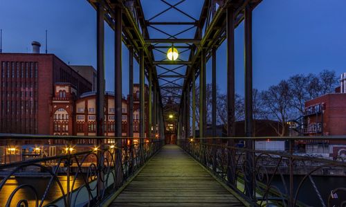 Illuminated footbridge against sky at dusk