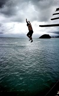 Man jumping on beach against sky