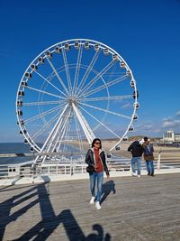 People in amusement park against blue sky